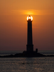 Faro marítimo con el sol poniéndose detras iluminando la bombilla en el Port de Goury, Normandia Francia, viajando en verano de 2022