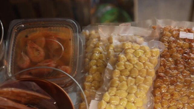 Close-up of a refrigerated display case offering various packaged snacks, including pickled shrimp, smoked cheese strings, and other seafood and cheese products. Variety of appetizing treats.