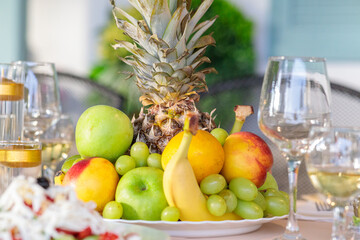Vibrant, fresh fruit platter centerpiece with pineapple, green and red apples, juicy grapes, peach, and orange, set on a bright table for a celebration or healthy dessert