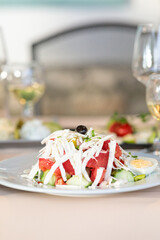 gourmet shobska salad (shopska) with fresh tomatoes, cucumbers, and shredded white cheese, garnished with olives and boiled egg, healthy restaurant meal