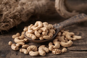 Fototapeta premium Cashew nuts displayed on a vintage spoon with rustic wooden background