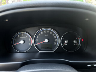 Speed and fuel gauges display the essential data as the vehicle prepares for a journey on a sunlit day in a busy city location