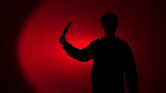Man's dark silhouette lifts a large kitchen knife against a blood red background