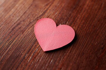 Vintage heart-shaped paper note on wooden surface with texture and isolated design