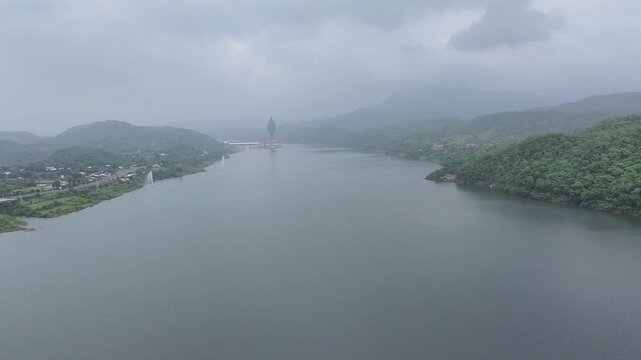 Statue of Unity and Narmada river surrounded by lush green mountains 