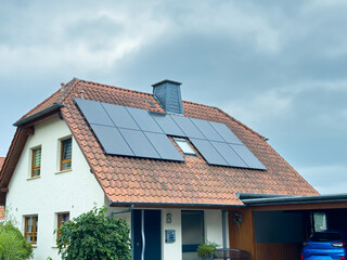 Solar panels transform a residential roof into a modern energy source under cloudy skies, showcasing sustainable living in a suburban neighborhood