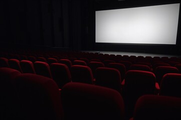 Fototapeta premium Rear view of vacant crimson theater chairs facing a bright display