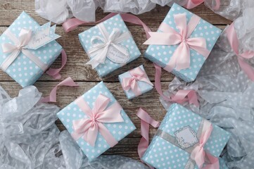 Gift boxes adorned with blue polka dots and pink bows set on a wooden surface