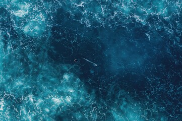 Aerial perspective of the sea showing waves, foam, and a surfer in the water
