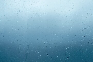 Glass Surface Covered with Raindrops Against a Blue Backdrop