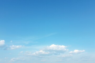 Clear blue sky with white clouds underneath and ample space for text