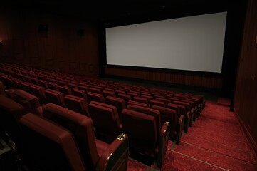 Fototapeta premium Interior of a vacant theater with red seats and a white projection screen, viewed from the side