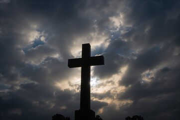 Silhouetted graveyard cross under a moody overcast sky