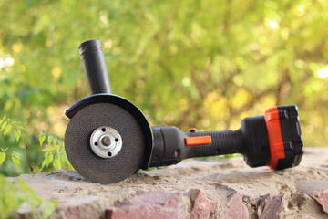 Angle grinder with battery. Power tool close-up. Angle grinder on the veranda. Repair and construction tool. Angle grinder with handle