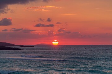 Fototapeta premium Stunning vibrant dawn over the ocean with striking clouds and glowing sunlight