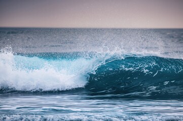 Fototapeta premium The azure ocean waves form a stunning display of nature's strength, enticing surfers to enjoy the beachfront hotel and immerse themselves in the experience