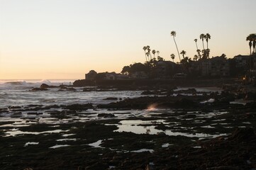Secluded coastal shorelines with sunsets, shadow figures, tide pools, surf waves, palm trees, and unique beach rock formations at a famous surf spot.