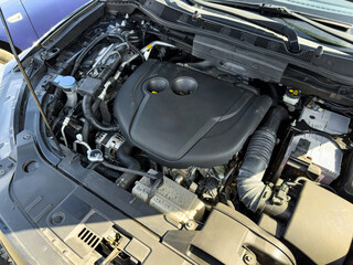 Engine components of a modern car showcased under the hood during a sunny day in a parking lot