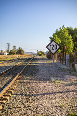 Fototapeta premium Valencian Community, Province of Alicante, Costa Blanca, Spain. A quiet view of the platform edge at Torrellano train station with railway tracks leading into the distance