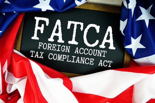 American flag with blackboard  "FATCA Foreign Account Tax Compliance Act" on wooden background
