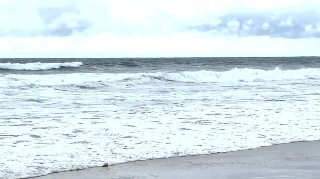 Listening and looking at the Side view of Atlantic Ocean Waves Rolling to the shore with birds flying back and forth.