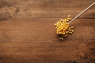 Fototapeta premium Spoonful of crispy fried corn resting on a rustic wooden surface with ample blank area