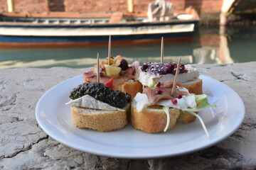 Appetizer bread bites on plate by canal in Venice bacaro Venetian cicchetti  