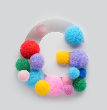 Colorful letter G made of fluffy pom poms on white background. Creative handmade typography for kids learning alphabet, educational design, playful classroom decor, and graphic projects.