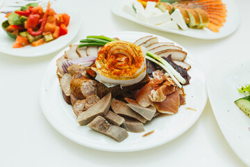 Culinary delight featuring an array of traditional dishes on a white platter during a festive gathering in a cozy setting