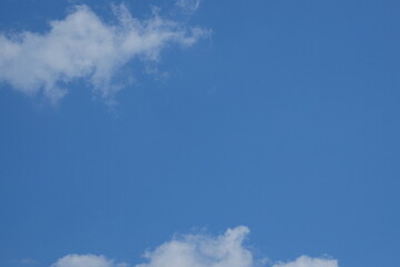 Clear blue sky with soft white clouds scattered throughout, creating a serene atmosphere ideal for backgrounds or design projects with copy space