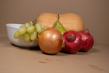 Autumn Harvest: Butternut Squash, Pear, Grapes, and Pomegranates on Brown Background