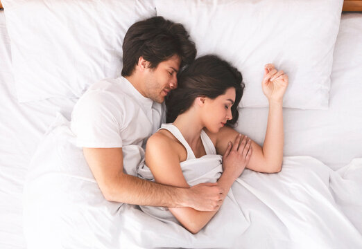 Loving married couple sleeping in bed and hugging, love and tenderness concept, top view - Powered by Adobe