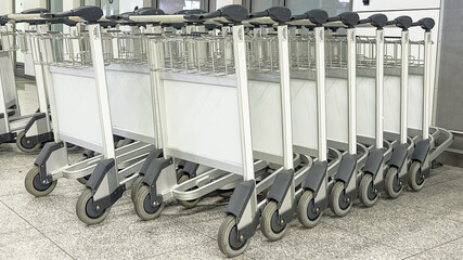 Airport luggage trolleys lined up in terminal, baggage carts in a row at international airport
