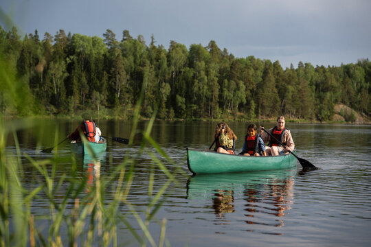 Female guide canoeing with kids in lake at summer camp