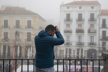 Retrato de un chico joven paseando por el casco antiguo de Cáceres un día con niebla