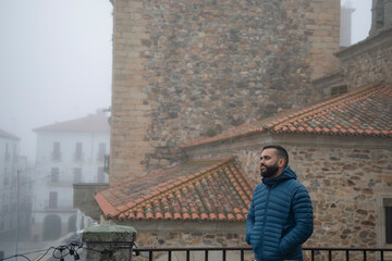 Retrato de un chico joven paseando por el casco antiguo de Cáceres un día con niebla