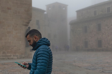 Retrato de un chico joven paseando por el casco antiguo de Cáceres un día con niebla