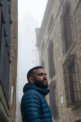 Retrato de un chico joven paseando por el casco antiguo de Cáceres un día con niebla