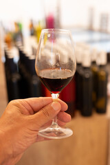 Hand with glass of Banyuls AOC aged natural sweet grand cru Banyuls fortified dessert wine from vines from slopes Pyrenees in Roussillon, France made in glass jar Dame Jeanne, demijohn
