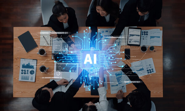 A top-down view of a business meeting where professionals engage with AI technology, showcasing data analysis tools and modern collaboration strategies in a vibrant office. Trope - Powered by Adobe