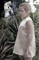 A vintage portrait of a seven-year-old girl in profile, wearing a short dress and a white bow in...