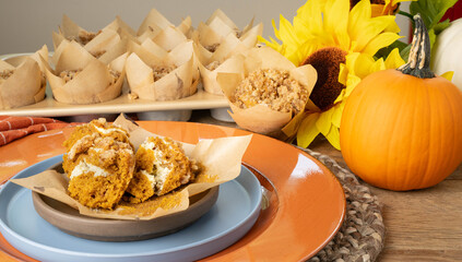 Unwrapped, fresh baked, pumpkin cream cheese muffin with streusel topping on a plate, ready to eat.