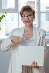 Portrait of emotional woman. Confident woman showing direction with hand on white sheet of paper with space for tex. Looking at camera, banner. Vertical photo. High quality photo
