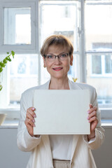 Portrait of emotional woman. Confident woman showing direction with hand on white sheet of paper with space for tex. Looking at camera, banner. Vertical photo. High quality photo