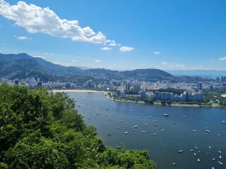 Fototapeta premium Panoramic view of Rio de Janeiro with mountains, city skyline, and bright blue sky. The photos capture famous landmarks such as Sugarloaf Mountain and the Christ the Redeemer statue in the distance, w