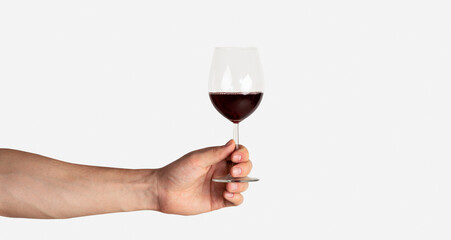 Male hand holding glass of red wine on light background, closeup with copy space. Panorama