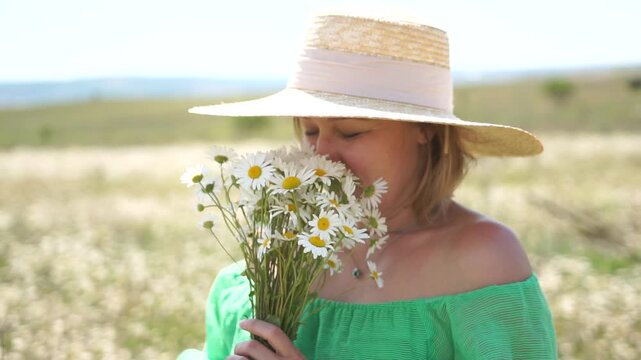 A woman wearing a straw hat and holding a bouquet of flowers in a field