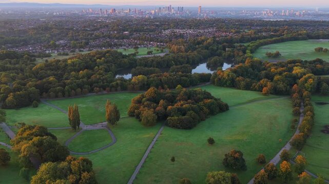 Aerial video of a golden sunrise over Heaton Park fields, woodland, and Manchester city skyline in the distance.
