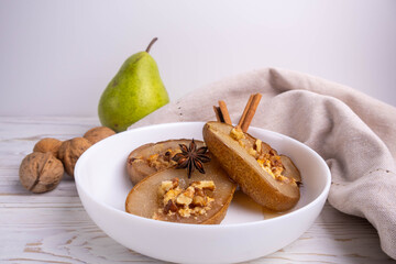 baked pear with honey, cheese, and nuts on a white plate.Baked pear with honey, cheese, and nuts on a white plate. The dish is presented for serving in a restaurant.