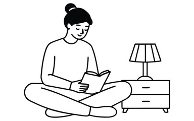 Young woman sitting cross legged reading a book next to a bedside table with a lamp
